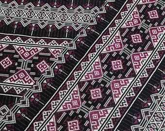 Pode incluir: Tecido preto com um padrão geométrico rosa e branco. O tecido tem uma textura tecida e um design diagonal.