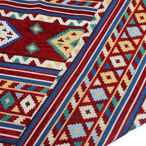 May include: Close-up of a red, blue, and yellow patterned fabric with a geometric design. The fabric is folded over, showing the intricate details of the pattern.