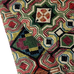 May include: Multicolored fabric with a geometric pattern featuring squares, circles, and diamonds. The fabric is woven with a variety of colors, including red, green, blue, yellow, and black.