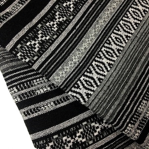 May include: Black and white striped fabric with a geometric pattern. The fabric is woven with a variety of textures and patterns.