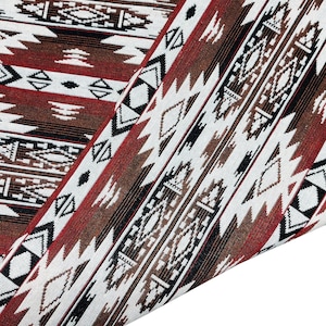 May include: Close-up of a red, brown, black, and white woven fabric with a geometric pattern. The fabric is folded in half, showing the pattern on both sides.