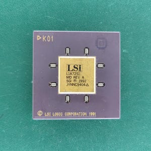 Könnte beinhalten: Ein quadratischer, violetter integrierter Schaltkreis-Chip mit einer zentralen, goldfarbenen quadratischen Platte mit dem Text LSI L1A7251 MD REV A SGI 1992 JYNNC9404. Der Chip hat acht kleine metallische Kontaktpunkte und den Text LSI LOGIC CORPORATION 1991.