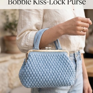 Könnte beinhalten: Eine hellblaue Häkeltasche mit Bobble-Stich-Textur und einem silberfarbenen Metall-Kussverschluss mit zwei Tragegriffen. Der Text PDF Crochet Pattern Bobble Kiss-Lock Purse und Bonus Free Tote Bag Pattern ist deutlich zu sehen.