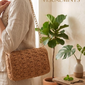 May include: A brown crochet handbag with a gold chain strap. The bag has a textured, patterned design and a rectangular shape. The brand name "VISUALMINTS" is visible in the upper right corner.