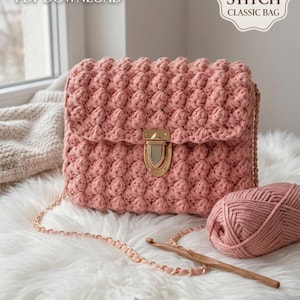 Könnte beinhalten: Eine altrosa Häkeltasche mit Noppenmuster, einem goldfarbenen Metallverschluss und einer passenden Kettenriemen. Das Bild enthält den Text CROCHET PATTERN PDF DOWNLOAD und BOBBLE STITCH CLASSIC BAG, sowie ein Knäuel rosa Garn und eine Häkelnadel aus Holz.