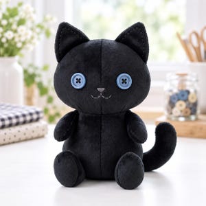 May include: A plush black cat toy with a soft, velvety texture. The cat features two light blue button eyes sewn on with black thread, a small embroidered gray nose, and a stitched mouth. It is in a seated position with a curved tail.