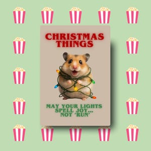 Peut inclure: Carte de Noël avec un hamster entouré de guirlandes lumineuses. La carte indique "CHRISTMAS THINGS" et "MAY YOUR LIGHTS SPELL JOY... NOT 'RUN'". Le fond est vert clair avec des graphiques de pop-corn.