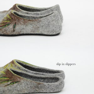 May include: Two pairs of gray felt slippers with a green and brown floral design. The top pair has a back, while the bottom pair is a slip-on style.