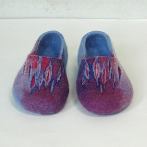 May include: A pair of blue and purple wool slippers with a red and white pattern. The slippers are made of felted wool and have a rounded toe.