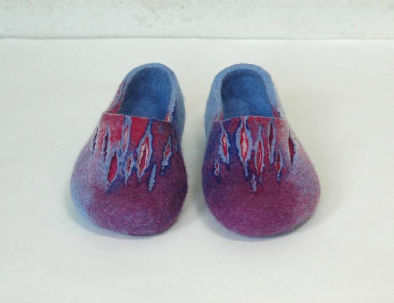 May include: A pair of blue and purple wool slippers with a red and white pattern. The slippers are made of felted wool and have a rounded toe.