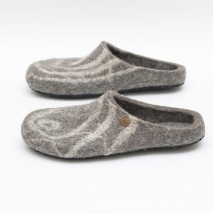 May include: A pair of gray wool slippers with a white swirl pattern. The slippers have a black rubber sole.