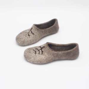 May include: A pair of brown felt slippers featuring a tree design. The slippers are soft and comfortable, ideal for keeping your feet warm during the winter months.