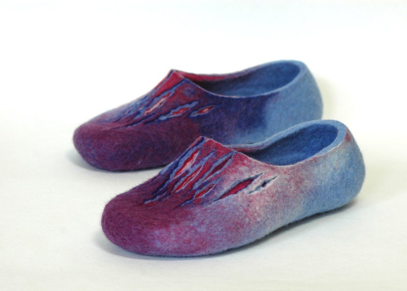 May include: A pair of blue and purple wool slippers with a unique design. The slippers have a gradient color scheme, fading from a deep purple to a light blue.