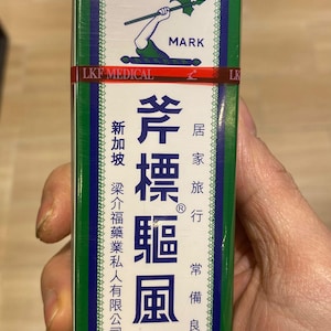 May include: A green and white box of Axe Brand Universal Oil. The box features Chinese characters and English text, including "TRADE MARK" and "LKF MEDICAL." The product is described as a remedy for home and travel use.