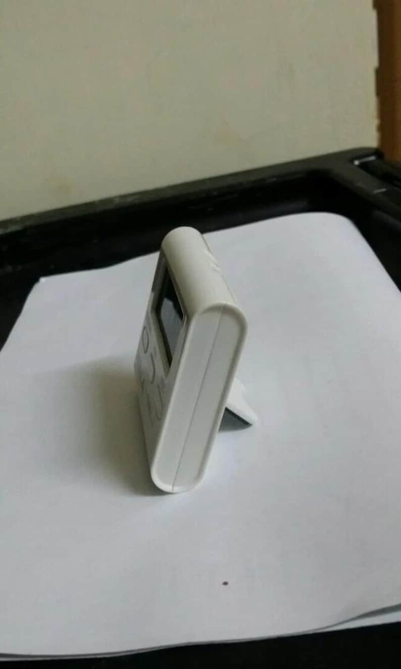 Pode incluir: Um temporizador de cozinha digital branco com um pequeno ecr&atilde;. O temporizador tem um topo curvo e um suporte na parte de tr&aacute;s, permitindo que fique em p&eacute;. O temporizador &eacute; feito de pl&aacute;stico.