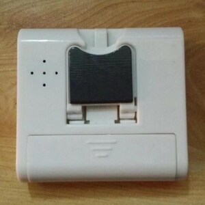 Pode incluir: Um dispositivo eletr&ocirc;nico retangular branco com uma se&ccedil;&atilde;o retangular preta no centro. O dispositivo possui uma s&eacute;rie de pequenos orif&iacute;cios no lado esquerdo e um mecanismo deslizante na parte inferior. &Eacute; provavelmente um pequeno gadget eletr&ocirc;nico.