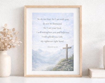 May include: A framed print featuring a serene landscape with a cross on a hill. The print includes the text of Isaiah 41:10, a Bible verse, in a soft, elegant font. The frame is light-colored, and the overall aesthetic is calming.