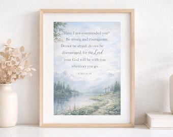 May include: Framed art print featuring a serene landscape with a lake, mountains, and a pathway. The print has a light blue and green color palette and includes the text "Have I not commanded you? Be strong and courageous..." in a script font.