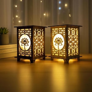 May include: Two decorative wooden lanterns with a lotus flower design. The lanterns have intricate cut-out patterns and emit a warm glow. The design includes geometric shapes and a central lotus motif, creating a calming atmosphere.