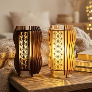 Może przedstawiać: Dwie drewniane lampy z ciepłym blaskiem. Lampy mają unikalny design z szeregiem pionowych drewnianych listew i geometrycznym wzorem pośrodku. Lampy stoją na drewnianej powierzchni.