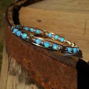 May include: A gold and silver wire wrapped bracelet with blue opal beads.