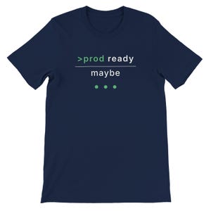 May include: Navy blue t-shirt with the text ">prod ready maybe" in white and green. The shirt has a crew neck and short sleeves. Three green dots are below the word "maybe".