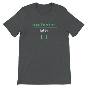 Puede incluir: Camiseta gris oscuro con el texto ">refactor later { }" en verde y blanco. Esta camiseta de manga corta y cuello redondo está diseñada para uso informal. El texto está centrado en el pecho.