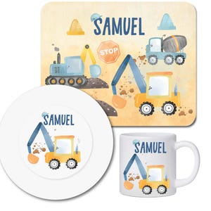 Könnte beinhalten: Ein Kinder-Set zum Thema Baustelle mit Platzset, Teller und Becher. Das Platzset zeigt eine Aquarell-Illustration von Baufahrzeugen und den Namen "SAMUEL". Teller und Becher haben ebenfalls ein Baufahrzeug-Design und den Namen "SAMUEL".