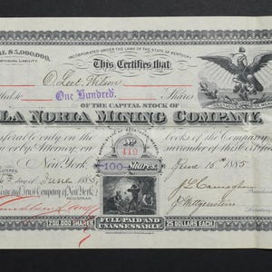 Könnte beinhalten: Antike Aktienurkunde der La Noria Mining Company vom 16. Juni 1885. Das Dokument weist verzierte Ränder, Text und ein Adleremblem auf. Die Urkunde gilt für 100 Aktien.