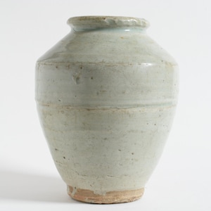 May include: A pale green ceramic vase with a rounded body and a slightly flared rim. The vase has horizontal bands and a textured surface. The base is a light brown color. The vase is approximately 8 inches tall.