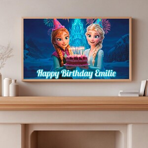May include: A framed print featuring animated characters from the movie Frozen holding a birthday cake with lit candles. The text "Happy Birthday Emilie" is displayed in a blue font. The print is displayed on a wooden mantel.