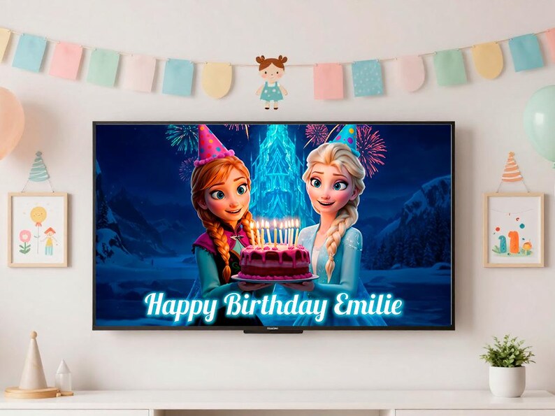 May include: A television screen shows a birthday scene with animated characters holding a cake with lit candles. The text "Happy Birthday Emilie" is displayed on the screen. The room is decorated with balloons, a banner, and framed artwork.
