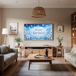May include: A living room scene with a large framed artwork that says "Happy Birthday" in a winter wonderland theme. The room features two gray sofas, wooden furniture, and a woven pendant light.