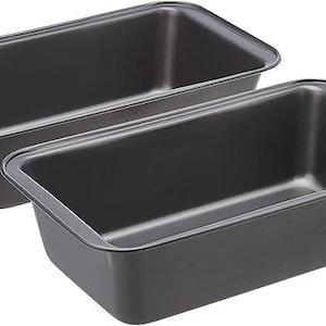 May include: Two dark gray rectangular loaf pans. The pans are made of metal and have a slightly rounded rim. They are empty and ready for baking. Perfect for making bread or cakes.