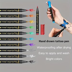 May include: A collection of black tattoo pens with gold accents, each with a different colored ink. The image also shows a red pen, a red cap, and a hand with a blue butterfly tattoo. Text on the image reads "Hand drawn tattoo pen".