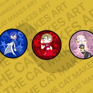 May include: Three circular art prints featuring cartoon characters. The first is a blue-themed character with stars, the second is a red-themed character, and the third is a pink and black character. The background is yellow with the text "THE CAT MAKES ART".
