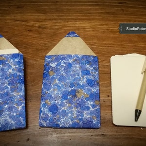 May include: Two blue and white marbled paper pencil holders with a stack of blank note cards and a pen on a wooden surface. StudioRobertWu/Etsy is visible in the image.