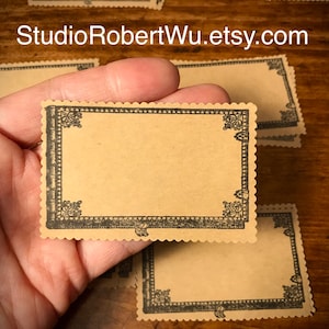 May include: A stack of blank, brown paper cards with a decorative black border. The cards are approximately 2.5 inches by 3.5 inches. The cards are perfect for writing notes, messages, or creating handmade cards.