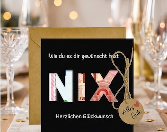 May include: A square black greeting card with the German text 'Wie du es dir gewünscht hast' and 'Herzlichen Glückwunsch' printed in white. The letters 'NIX' are cut out, revealing Euro banknotes behind them. A brown tag with 'Alles Gute' and a red heart is attached.