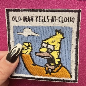 May include: Embroidered patch featuring a cartoon character yelling at a cloud. The patch has a blue background with a white cloud and the text "OLD MAN YELLS AT CLOUD". The character is yellow and wearing glasses.