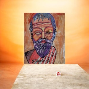 May include: A colorful portrait of Socrates with a long purple beard and the Greek text "Σωκράτης". The artwork features a red and white striped garment and is displayed on a light-colored surface.