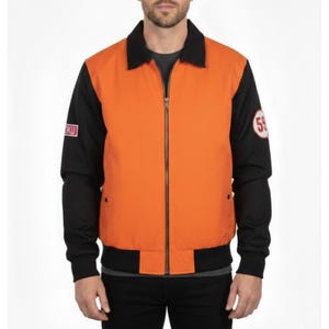 Puede incluir: Chaqueta naranja y negra con cremallera, cuello y puños negros. La chaqueta presenta un parche "59" en la manga y un pequeño parche "OKU" en la otra manga. La chaqueta es de estilo bomber.