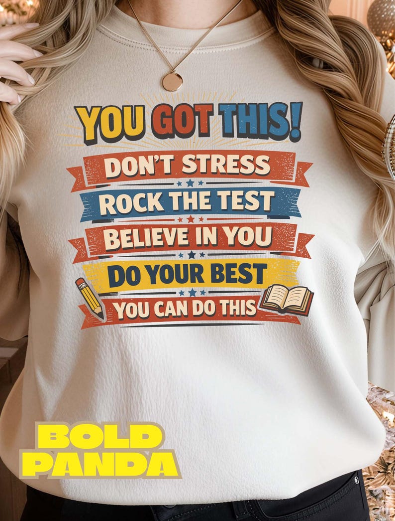 May include: Cream-colored sweatshirt with the text "YOU GOT THIS!" in yellow and red. Below, the shirt features the phrases "DON'T STRESS", "ROCK THE TEST", "BELIEVE IN YOU", "DO YOUR BEST", and "YOU CAN DO THIS". A pencil and book graphic are also included.