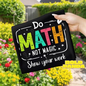 May include: Black rectangular fabric with the words "Do MATH Not MAGIC Show your work" in white, green, pink, and orange. The words are surrounded by white stars and lines. The words "BOLD PANDA" are in the bottom right corner.