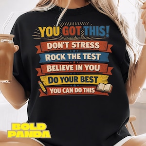 May include: Black sweatshirt with the text "YOU GOT THIS!" in yellow and blue. The design includes the phrases "DON'T STRESS", "ROCK THE TEST", "BELIEVE IN YOU", "DO YOUR BEST", and "YOU CAN DO THIS". A pencil and book graphic are also included.