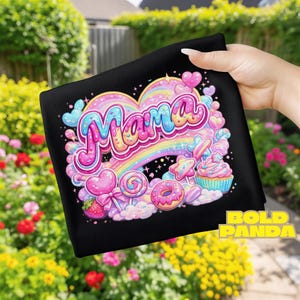Puede incluir: Tela negra con un gráfico colorido que dice "Mama" en letras de burbujas. El diseño incluye un arcoíris, corazones, piruletas, una magdalena y un donut. Las palabras "Bold Panda" están en la esquina inferior derecha.