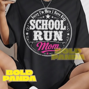 May include: Black t-shirt with a white and pink graphic. The graphic reads "Sorry I'm late I have kids" in a circular design, with "SCHOOL RUN Mom" in bold letters. A casual, everyday wear tee.