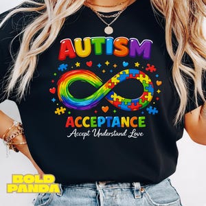 May include: Black t-shirt with the words "AUTISM ACCEPTANCE" in rainbow colors. The design includes a rainbow infinity symbol made of puzzle pieces, hearts, and stars. The text "Accept Understand Love" is below the word "ACCEPTANCE".