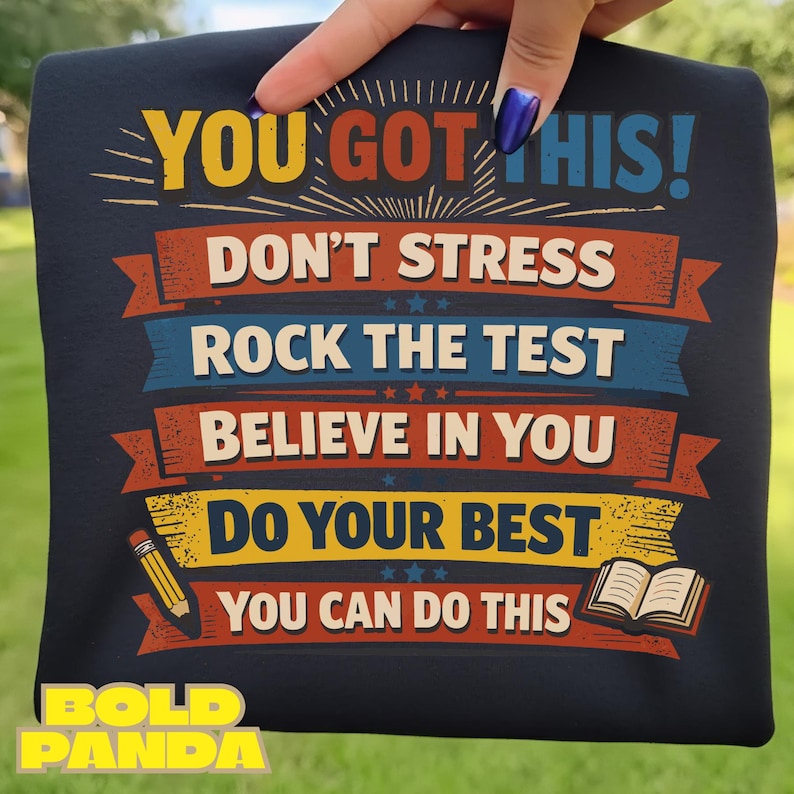 May include: Navy blue t-shirt with the text "YOU GOT THIS!" and other motivational phrases in a colorful design. Includes a pencil and book graphic. The brand name "BOLD PANDA" is at the bottom.