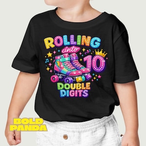 May include: Black t-shirt with a colorful graphic design. The design features roller skates, the words "Rolling into 10 Double Digits", stars, and a crown. The roller skates are pink, purple, and blue.